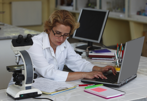 Scientist in laboratory types up notes