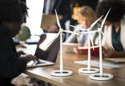 Academic researchers are surrounded by several miniature models of wind turbines