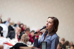 Female academic speaking from a podium delivers a conference